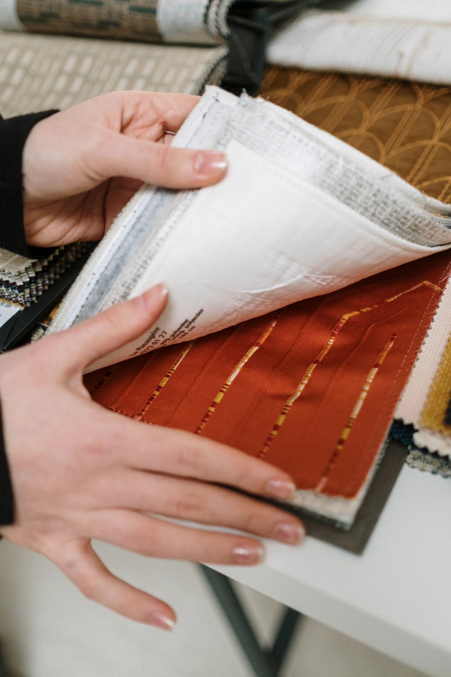 Hands turning fabric sample book pages during material evaluation
